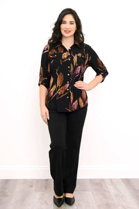 Woman wearing a black shirt with orange and purple leaf print, hand on hip