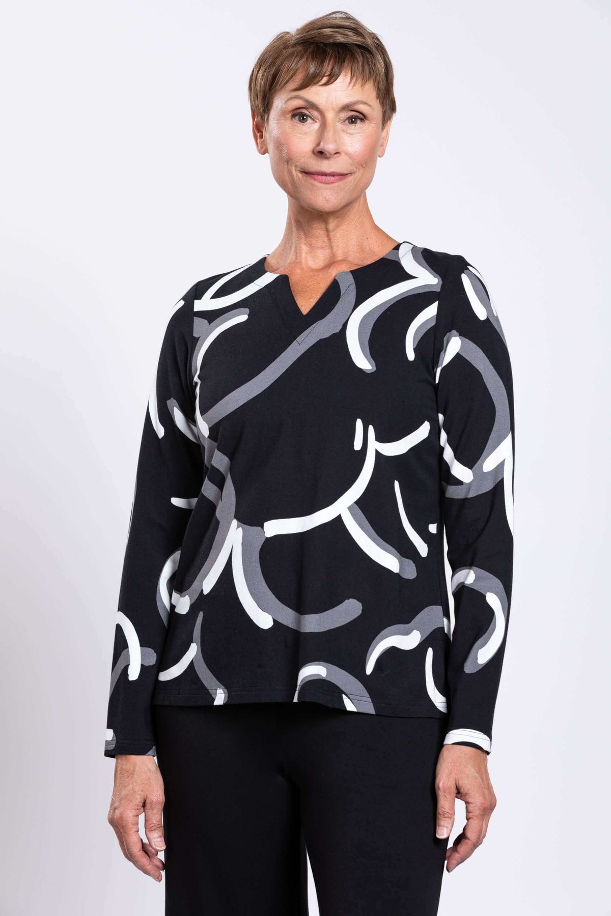 Front view of model wearing black long sleeve top with abstract white and grey swirl print