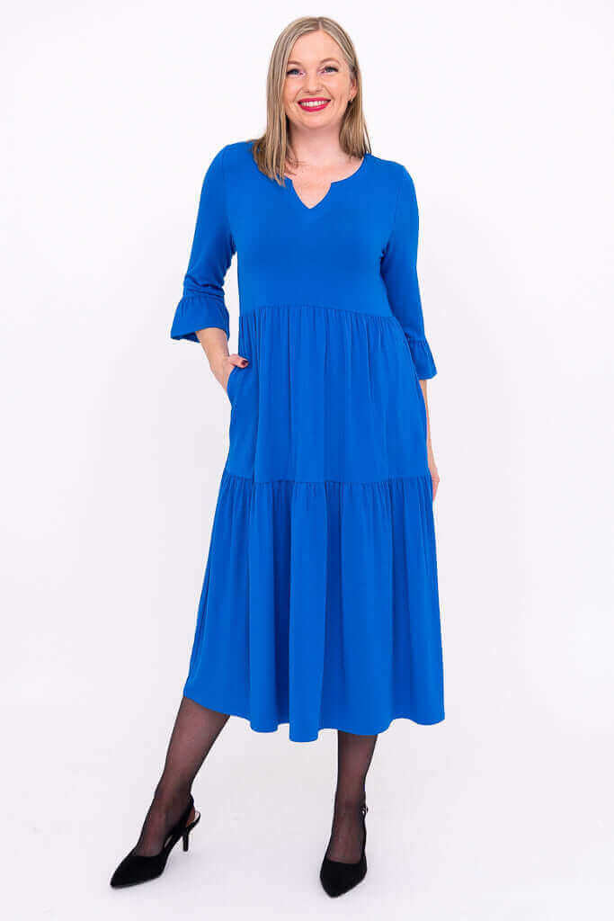Front view of a woman wearing a bright blue tiered midi dress with ruffle 3/4 sleeves