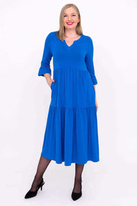Front view of a woman wearing a bright blue tiered midi dress with ruffle 3/4 sleeves