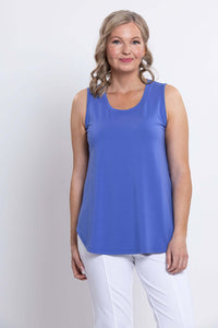 Front view of woman wearing a sleeveless blue bamboo tank top and white pants
