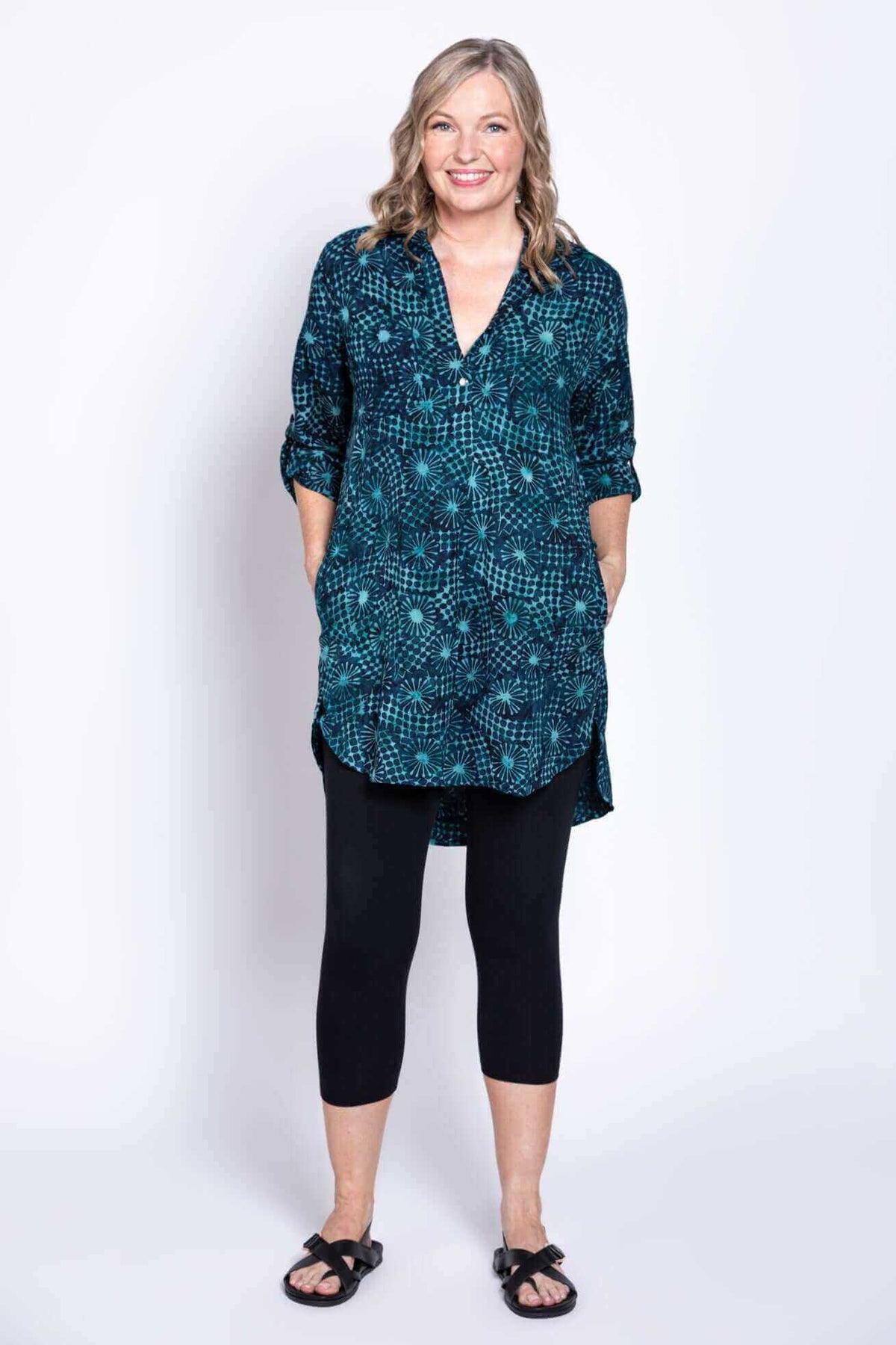 Front view of woman with hands in pockets, wearing blue batik tunic blouse