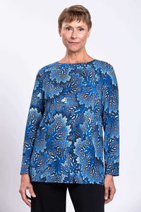 Close up front view of a woman wearing a blue botanical print bamboo top with a boat neckline.