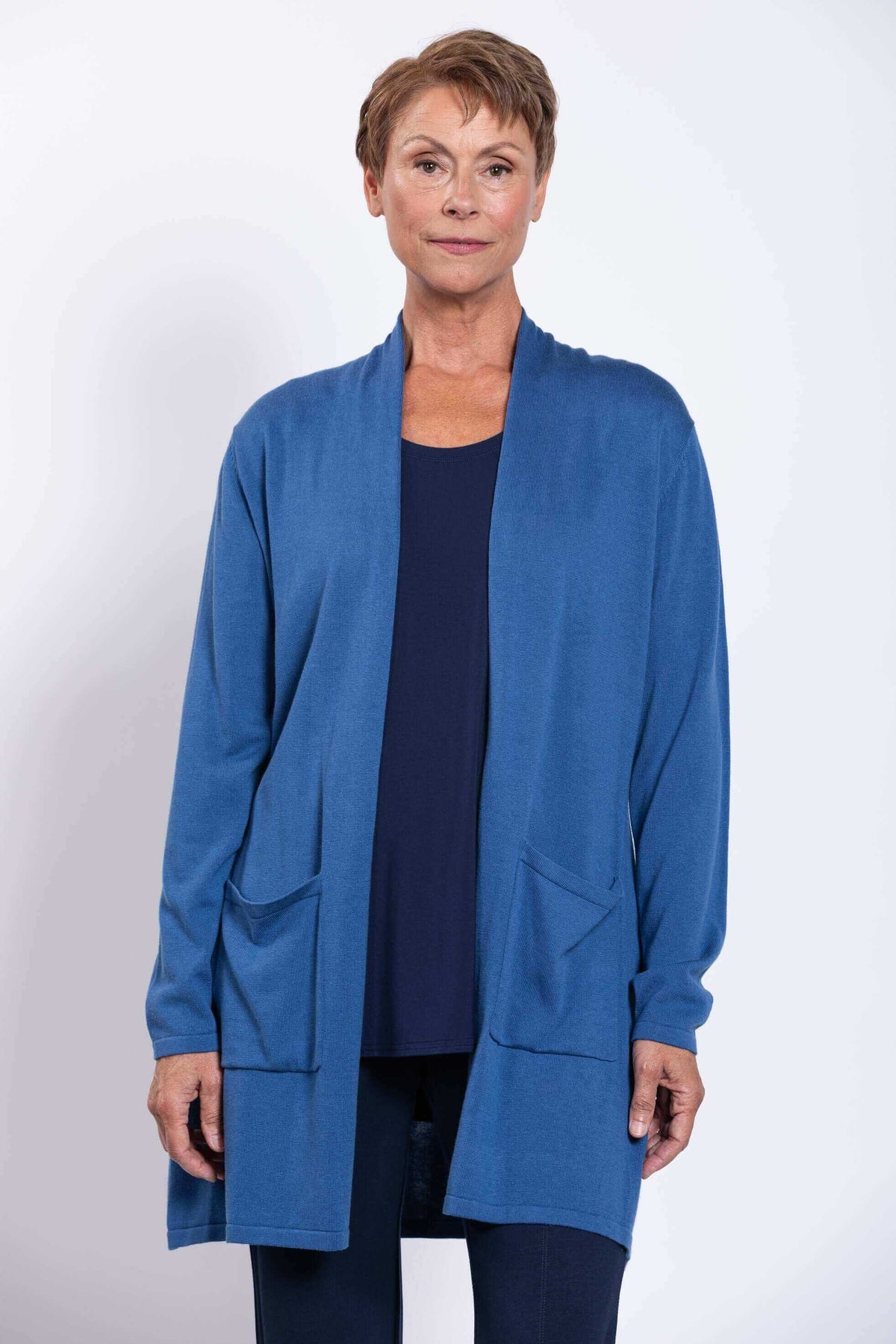Front view of woman wearing a lightweight blue cardigan with patch pockets