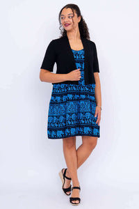 Woman in blue elephant print dress with black short-sleeve shrug, front view
