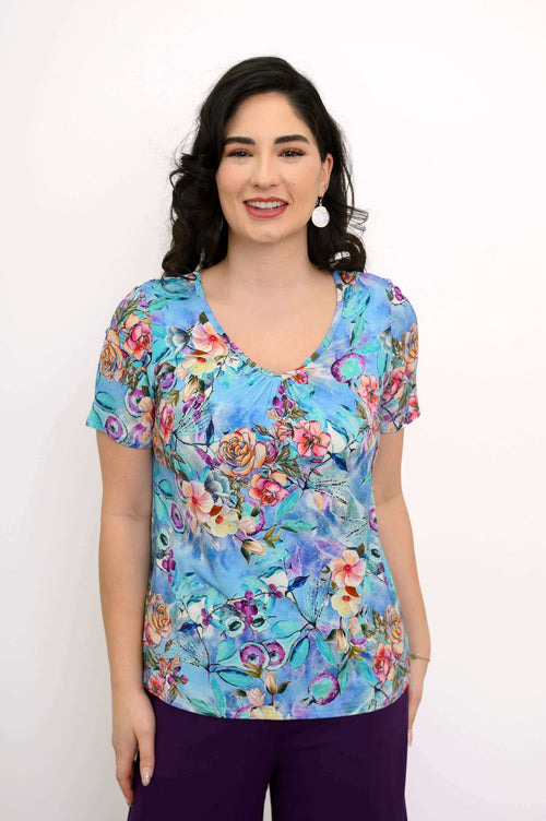 Front view of woman wearing a blue bamboo top with vibrant floral print