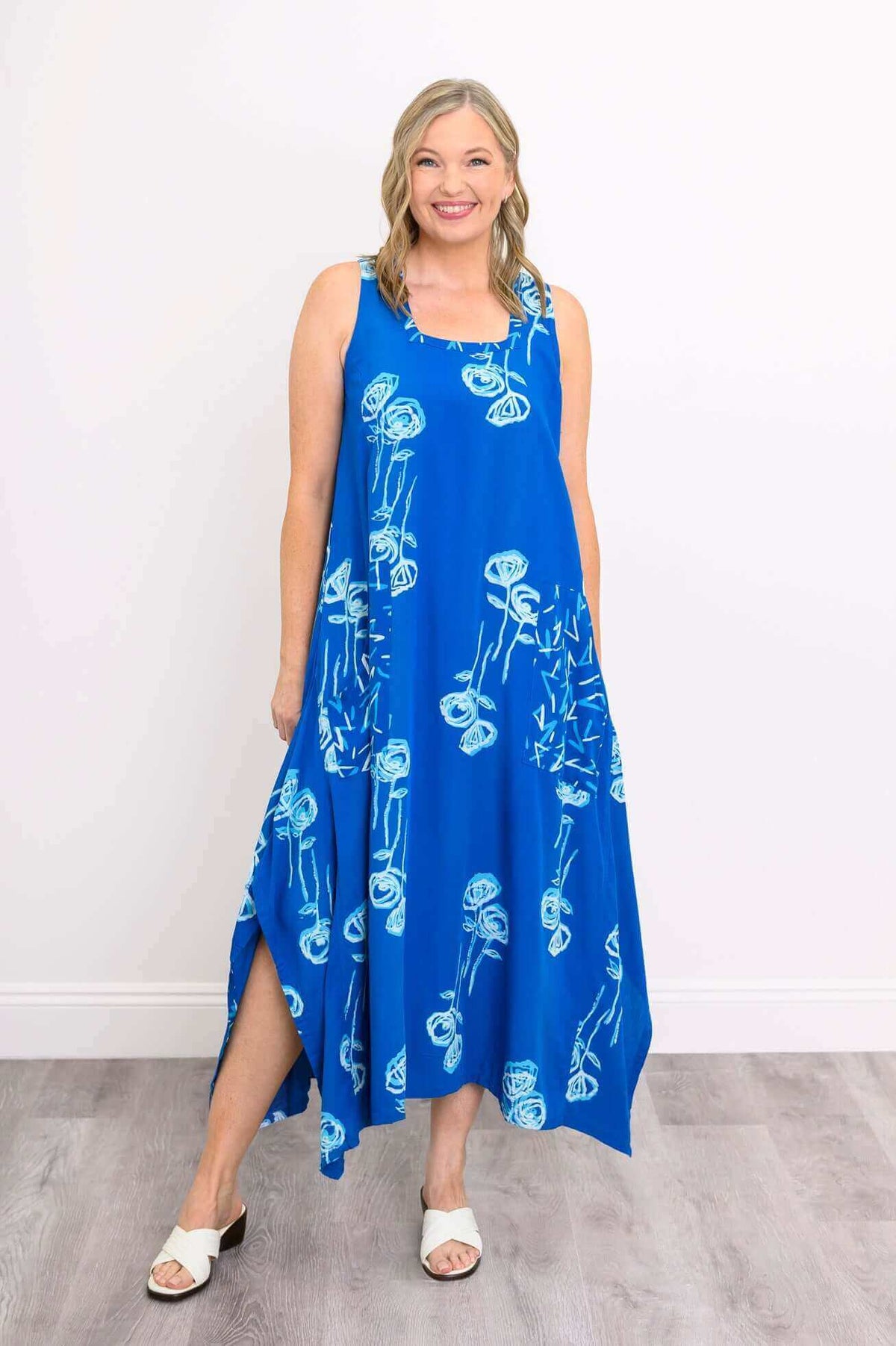 Front view of model wearing a blue floral sleeveless dress with square neckline