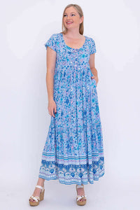 Front view of woman wearing blue floral tiered maxi dress with pockets