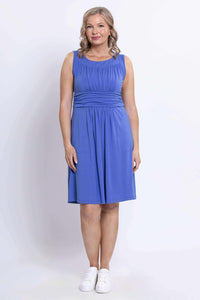 Front view of a woman wearing a sleeveless blue ruched dress with waistband and pockets