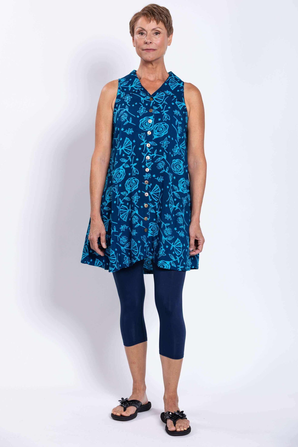 Front view of model in blue sleeveless floral tunic tank and navy leggings