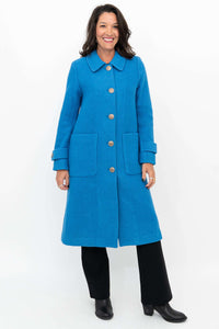 Woman wearing a blue wool coat with large buttons and front patch pockets