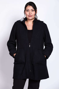 Front view of model wearing a black boiled wool car coat with patch pockets