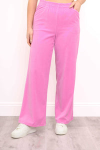 Front view of bright pink wide-leg corduroy pants shown with white sneakers