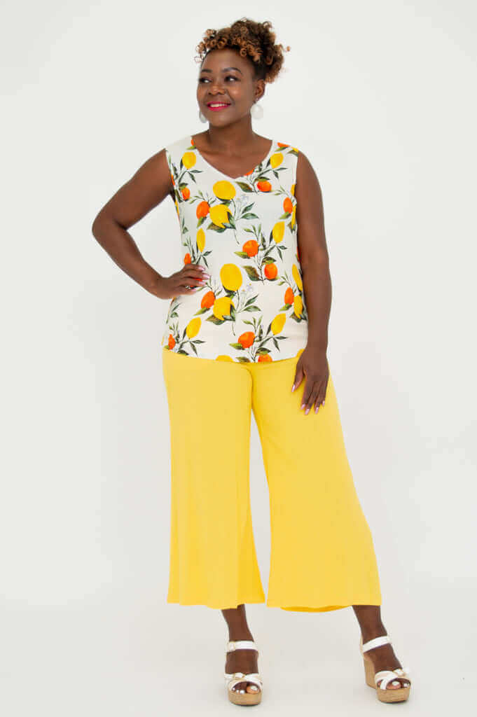 Front view of model wearing citrus print V-neck tank with yellow pants