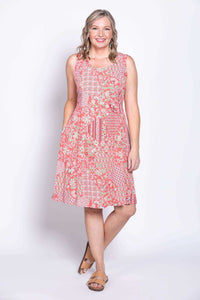 Woman smiling in a coral floral sleeveless A-line dress with patchwork patterns, front view