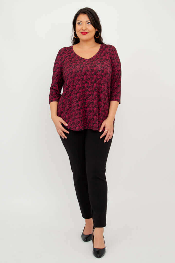 Front-facing model in coral print V-neck top, hands in pockets, black pants