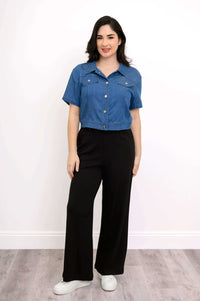 Front view of woman wearing cropped denim jacket with black pants and white sneakers