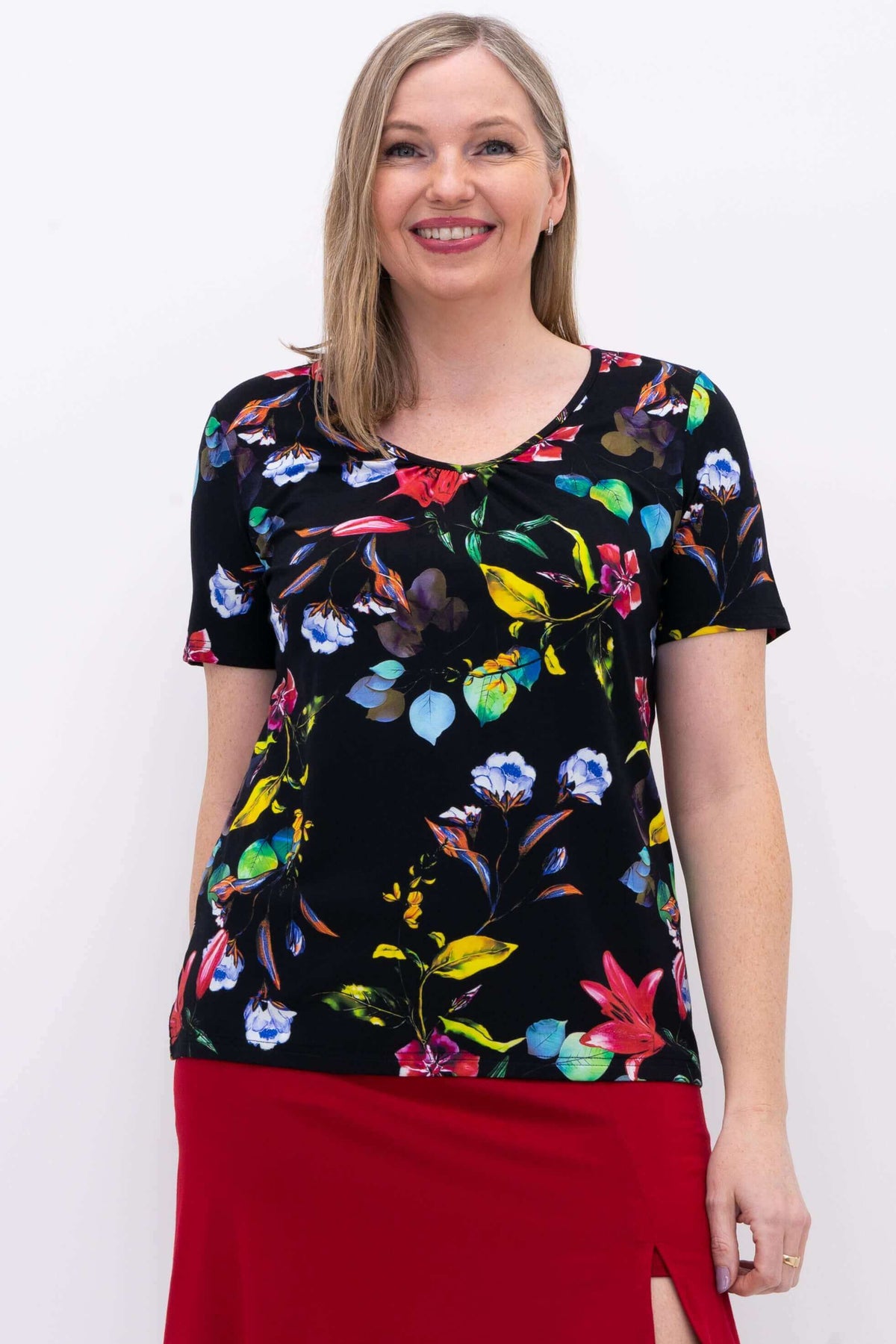 Front view of woman wearing a black bamboo top with a colorful floral print and red skirt