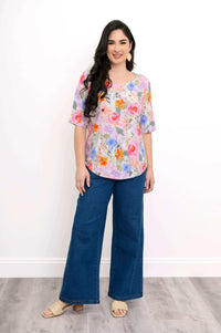Woman modeling floral scoop neck blouse with wide-leg jeans, front view