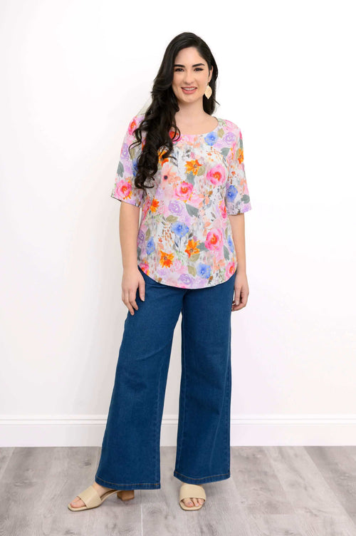 Woman modeling floral scoop neck blouse with wide-leg jeans, front view