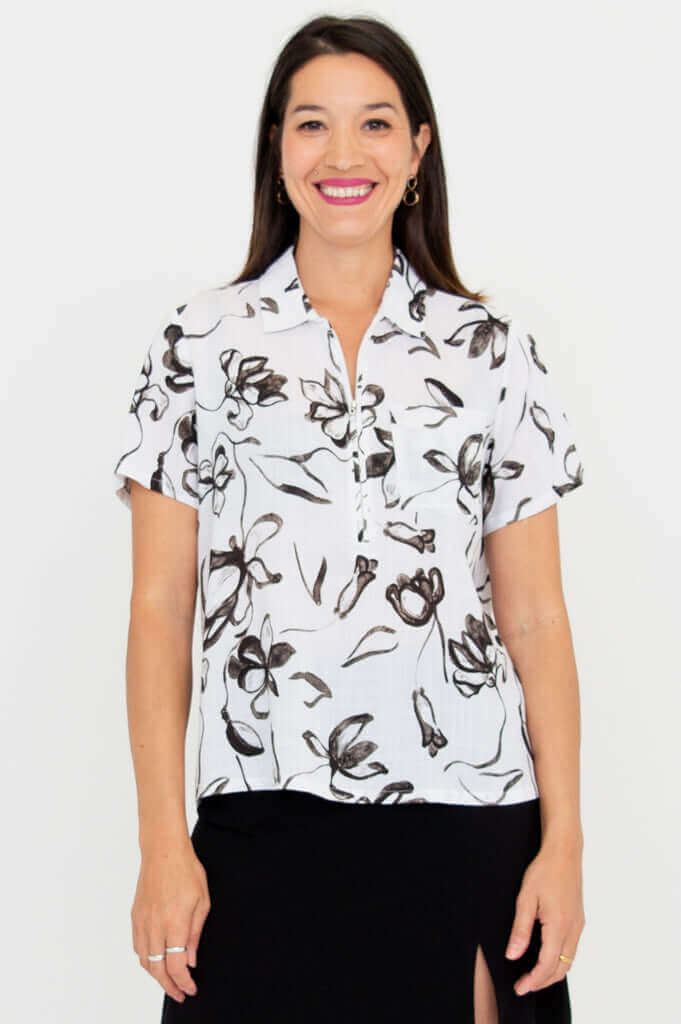 Woman wearing a white short-sleeve floral print top with collar and 3/4 zip, front view
