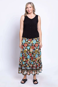 Front view of a woman in a sleeveless black top and floral tiered maxi skirt