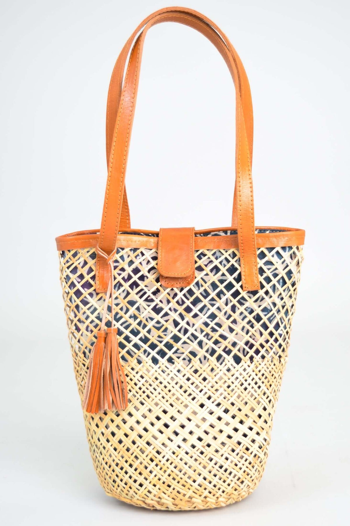 Front view of hand woven rattan basket with leather handles and blue printed lining