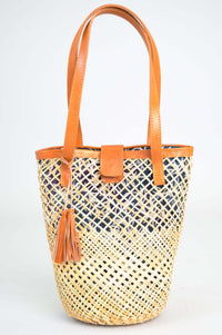 Front view of hand woven rattan basket with leather handles and blue printed lining