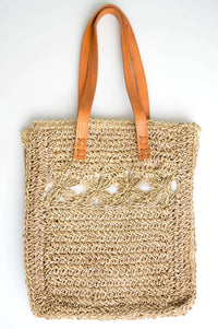 Front view of handwoven rattan tote bag with tan leather handles