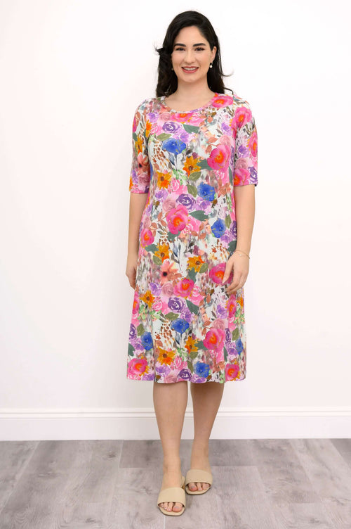 Woman wearing a knee-length, vibrant floral bamboo dress, front view