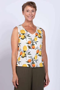 Front view of woman wearing a sleeveless white V-neck tank top with lemon and orange print