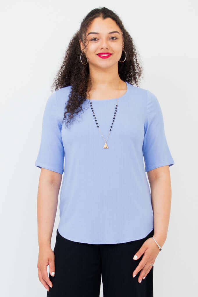 Front view of model wearing light blue tee style blouse with elbow sleeves