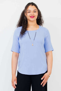 Front view of model wearing light blue tee style blouse with elbow sleeves