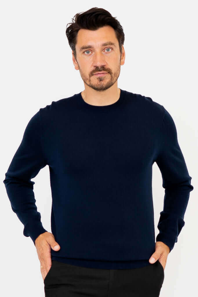 Front view of a man wearing a navy Merino wool sweater with black pants
