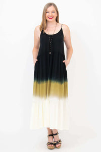 Front view of woman in a sleeveless black to golden ombre maxi dress with pockets