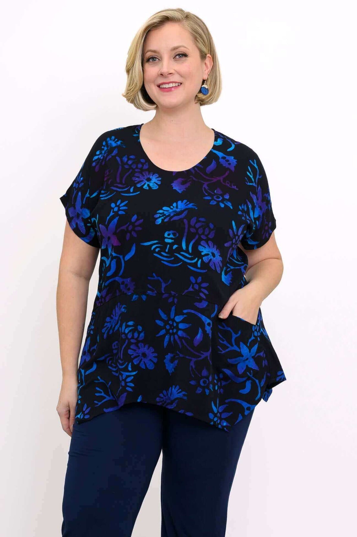 Front view of woman wearing a black curved-hem top with blue and purple floral print