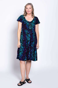 Front view of model wearing a black dress with teal and purple botanical print and flutter sleeves