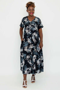 Front view of model in a black and white floral button-up dress with pockets