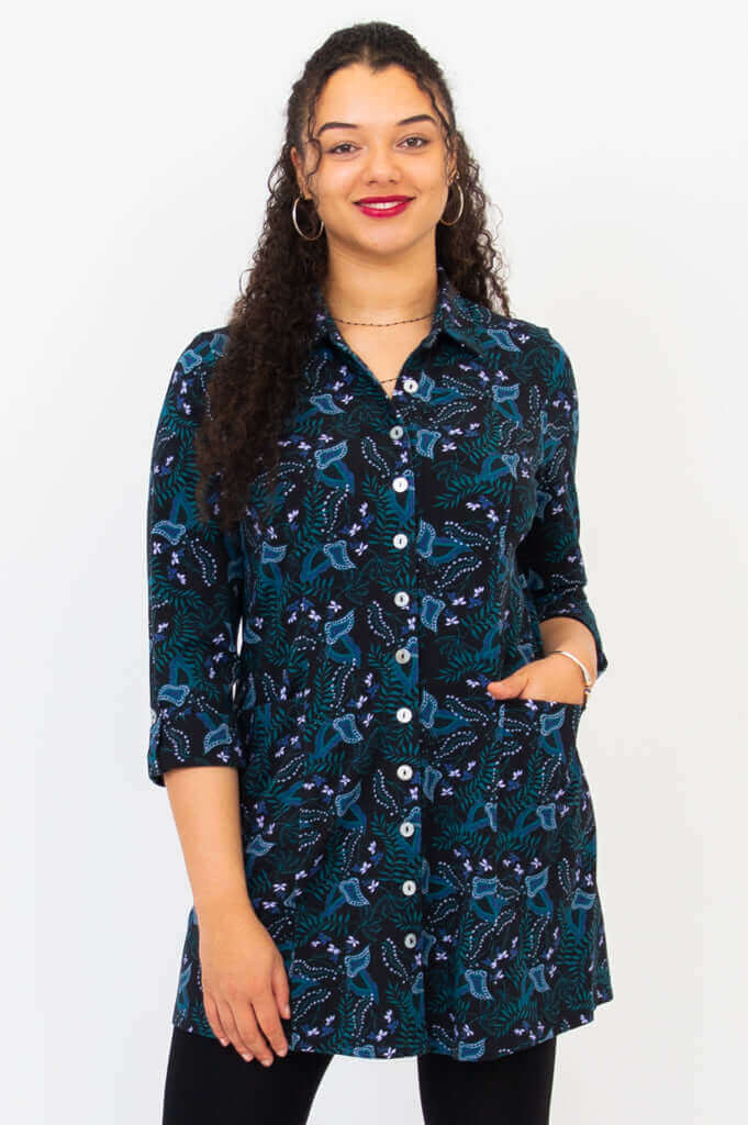 Front view of model wearing a black bamboo tunic shirt with blue and teal pattern