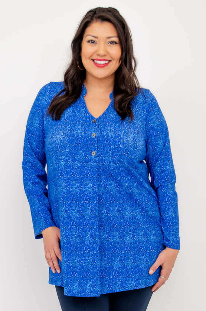 Model wearing a vibrant blue long sleeve V-neck tunic with a subtle pattern, front view