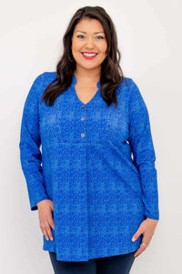 Model wearing a vibrant blue long sleeve V-neck tunic with a subtle pattern, front view