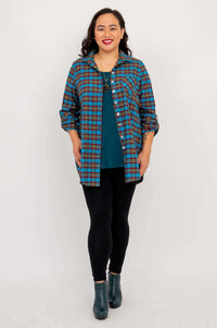 Front view of model in blue plaid flannel tunic, hands relaxed at sides