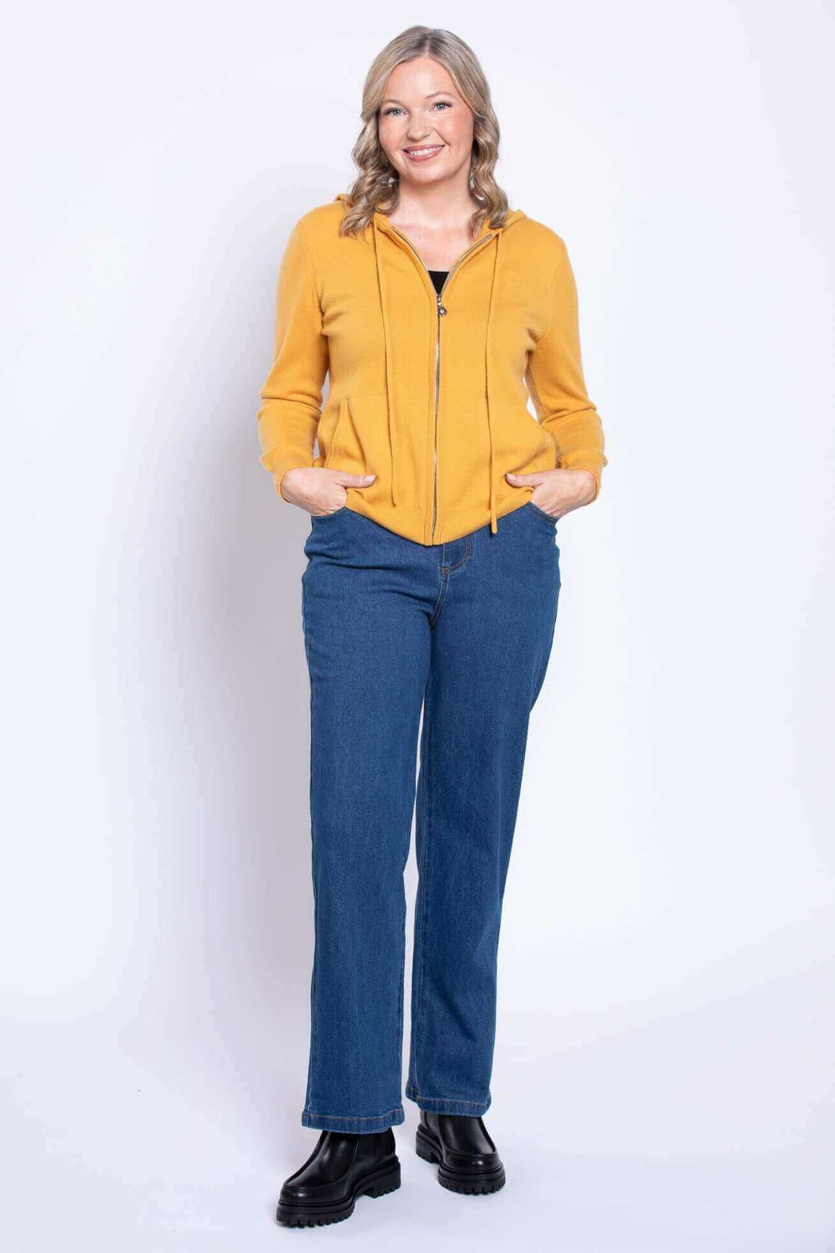 Front view of a woman wearing classic fit straight leg blue jeans with a yellow hoodie.