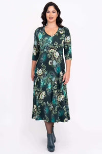 Front view of woman in a green floral midi dress with empire waist and floral pattern