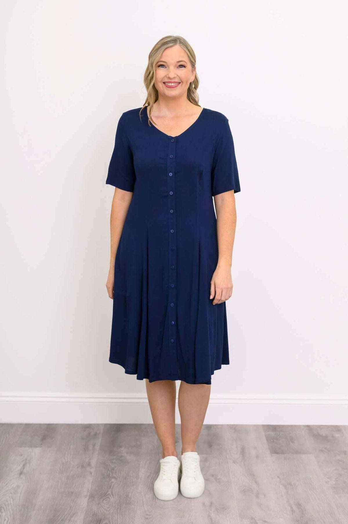 Front view of model in navy blue button-front dress with v-neck and short sleeves