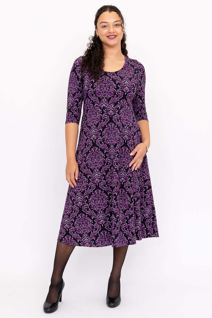 Front view of model wearing a purple damask midi dress with three-quarter sleeves