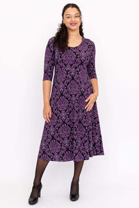 Front view of model wearing a purple damask midi dress with three-quarter sleeves
