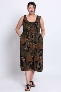 Front view of model standing in a sleeveless, flowy jumpsuit with safari animal print
