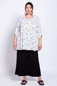 Front view of model in white floral bamboo linen tunic with black pants