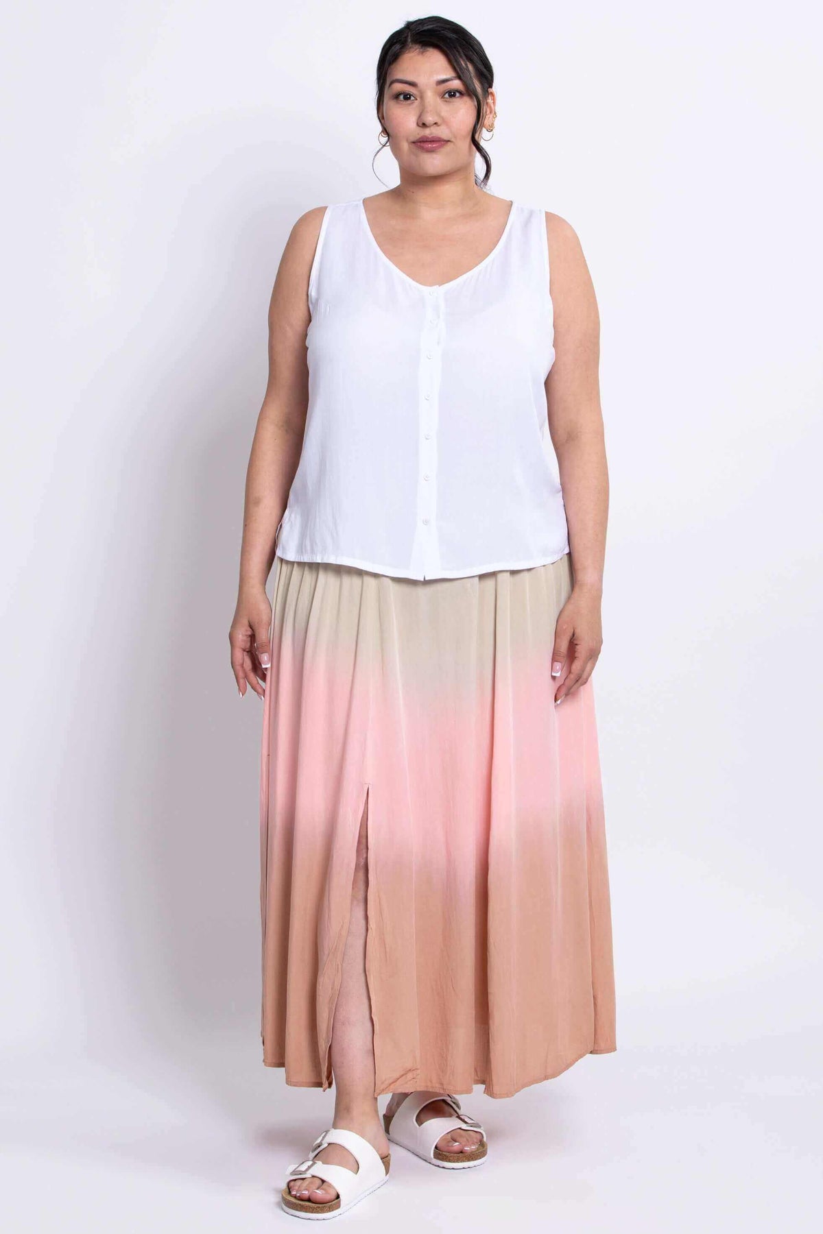 Front view of model in white sleeveless top and peach-pink dip-dye skirt with slits